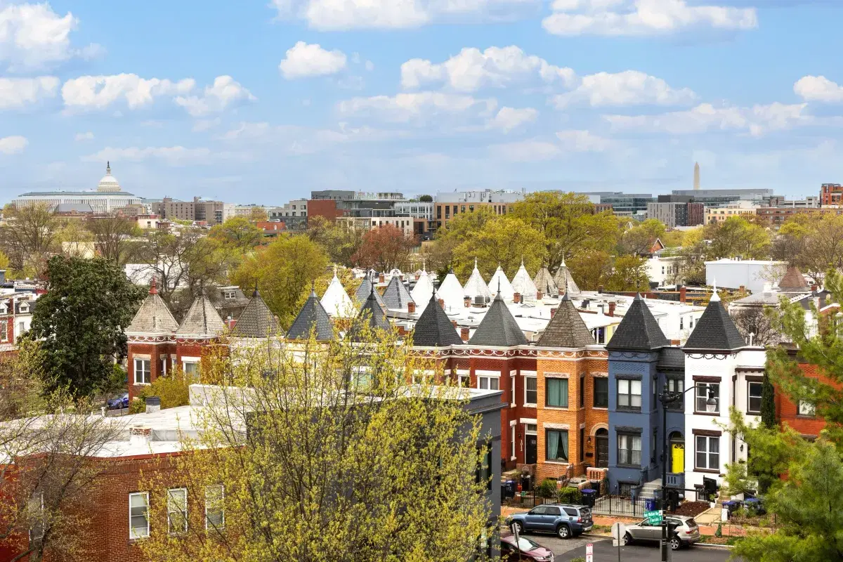 Turreted rowhouse roofs with the Capitol dome and Washington Monument on the skyline