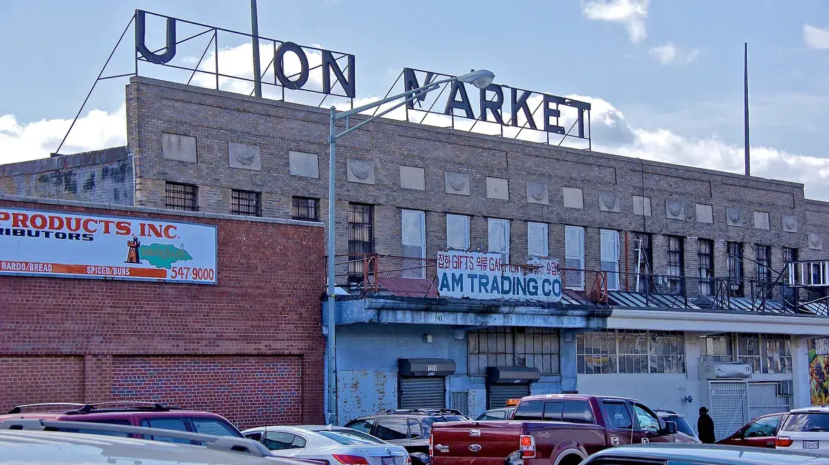 A brick market building with a rooftop Union Market sign above wholesale shops and parked trucks