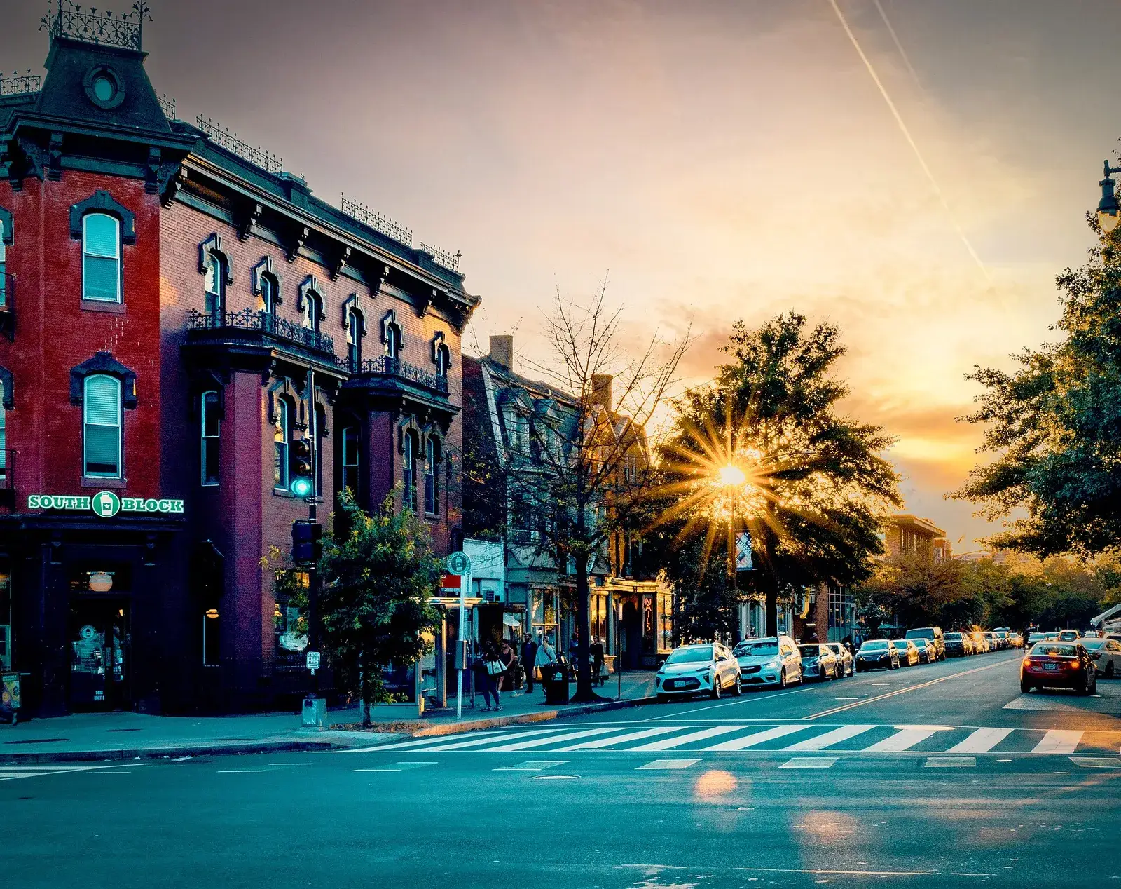 P Street NW in Logan Circle at sunset, with a red brick Victorian corner building and cars parked along the street, Washington, D.C.
