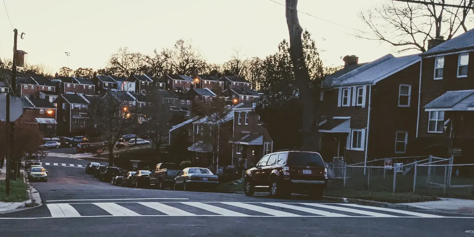 Brick semi-detached houses stepping up a hill on G Street SE in Benning Ridge at dusk