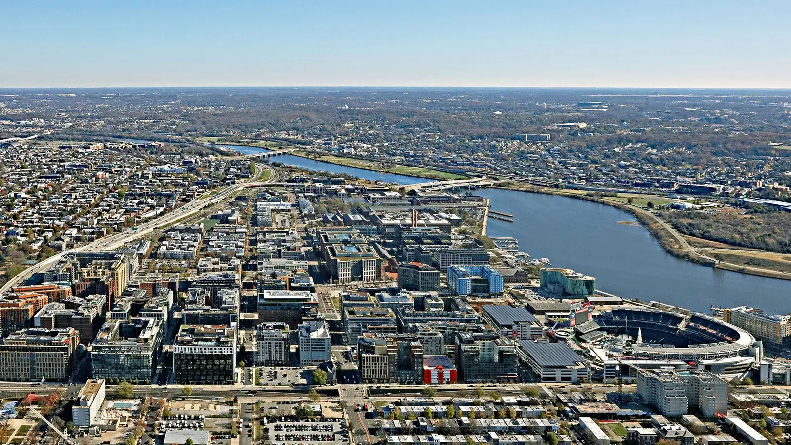 Aerial view of the Navy Yard skyline — new high-rises and their rooftops, Nationals Park, and the Anacostia River with the Frederick Douglass Bridge beyond, Washington, D.C.