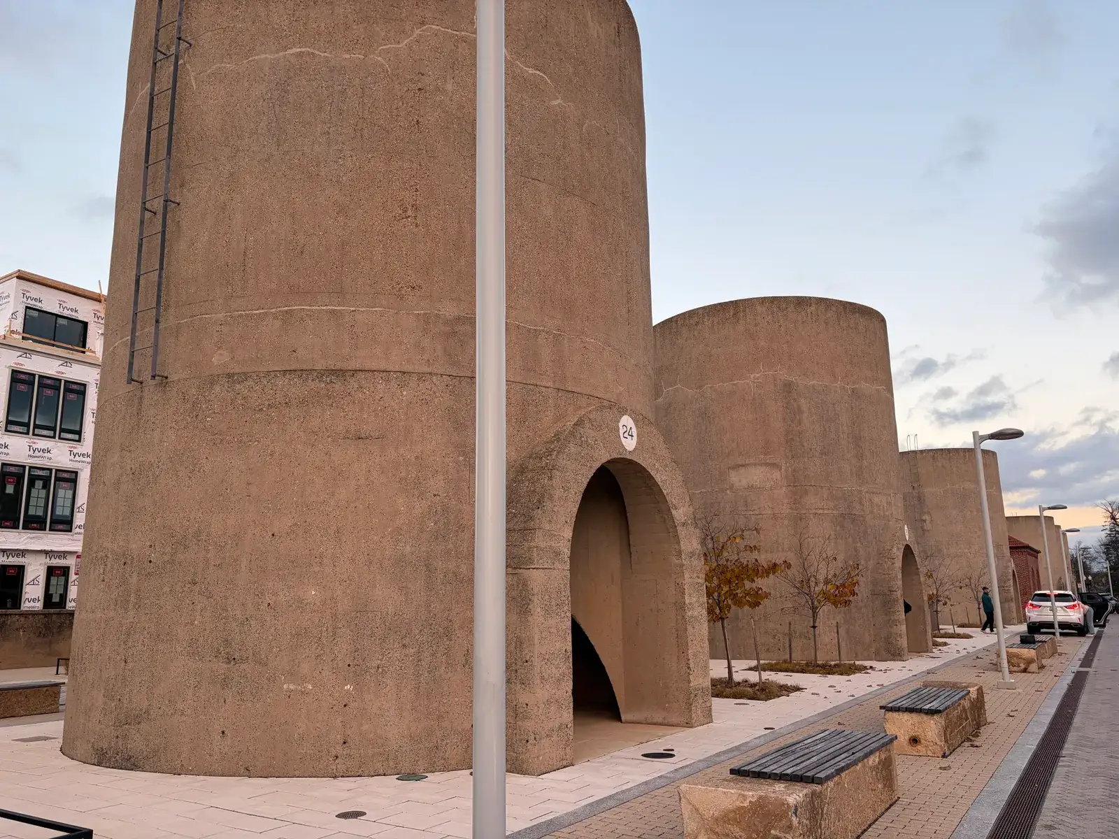 A row of tall concrete sand bins with arched openings along a plaza in the Reservoir District